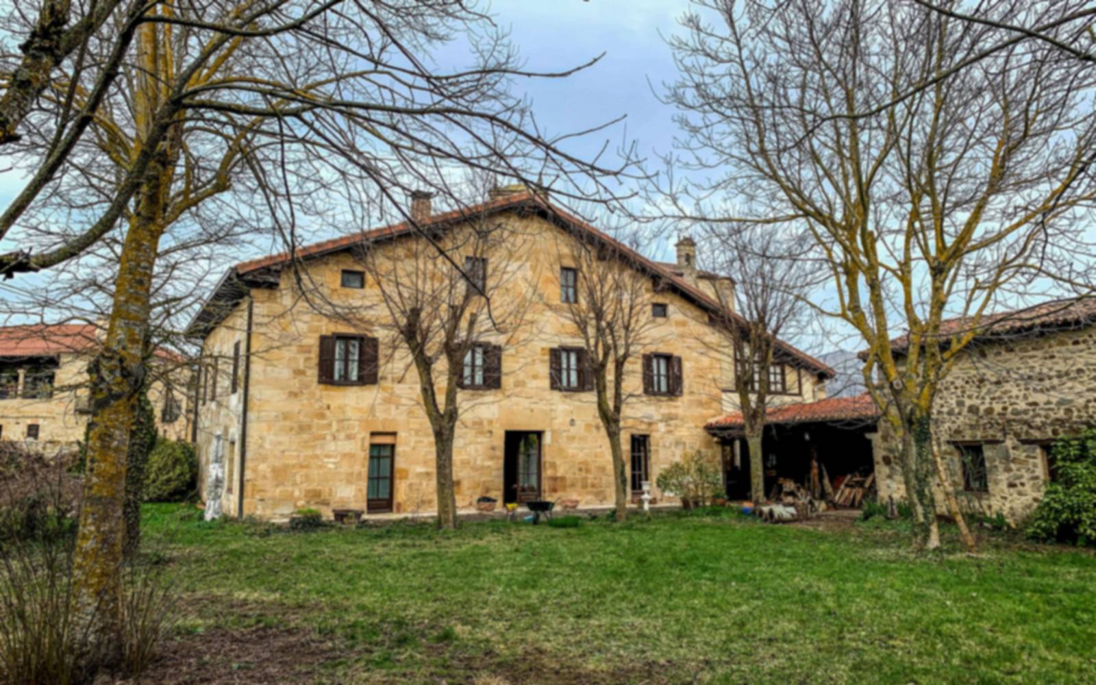 La grange en pierre et son jardin, entre de grands arbres